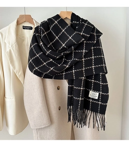 Detail of a black and white plaid scarf with tassels on neutral coats for winter