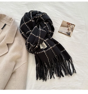 Detailed close-up of thick black and white plaid scarf featuring long fringe and soft texture
