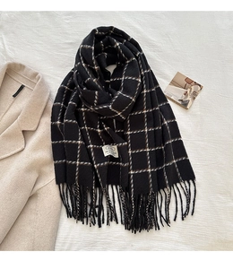 Detail of grid pattern wool blend scarf with fringe tassels on beige fabric
