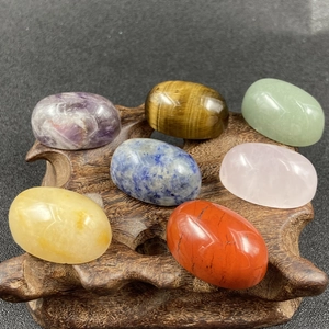 Polished natural chakra crystals on a wooden base including amethyst and tiger eye