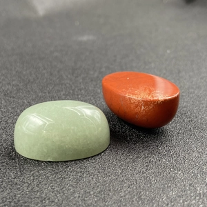 Polished oval cabochon gemstones in green aventurine and red jasper showing smooth texture