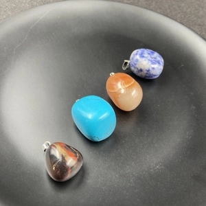 Vue rapprochée de quatre pendentifs en cristal minéral poli avec attaches en argent sur plateau