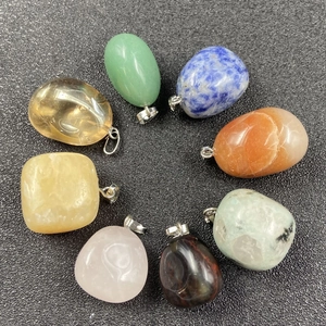 Vue détaillée de huit pendentifs en cristaux naturels colorés disposés en cercle sur fond noir
