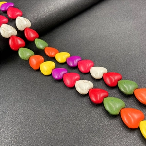 Colorful heart-shaped turquoise beads for DIY jewelry making displayed on a black surface