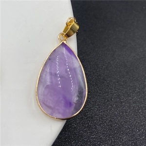 Détail macro du pendentif améthyste violette avec bordure dorée élégante en goutte