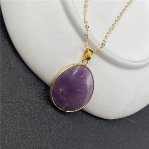 Gros plan d'un pendentif ovale en améthyste violette avec bords gravés en métal doré
