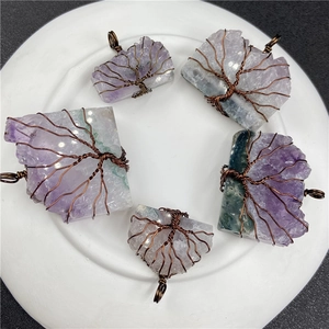 Five amethyst tree of life wire wrapped pendants arranged on a white ceramic plate