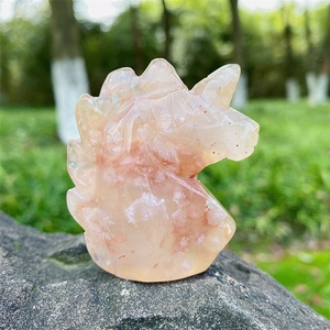 Scultura di unicorno in agata fiore di ciliegio naturale su roccia in una foresta