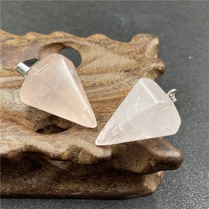 Detailed view of two natural pink crystal hexagonal pendants on carved wooden stand