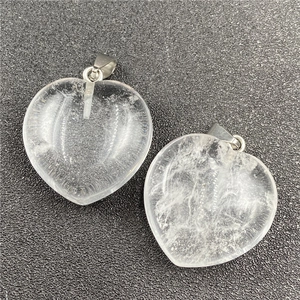 Macro shot of two transparent heart crystal pendants with silver metal clasps on a black mat