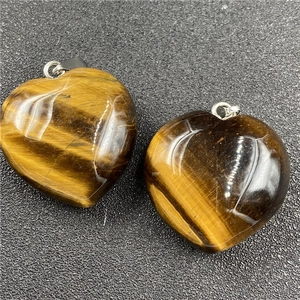 Macro shot of two polished heart-shaped tiger eye stone pendants with silver clasps