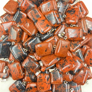 Macro shot of rectangular polished red and black obsidian pendants with metal buckles
