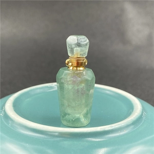 Macro shot of green fluorite crystal perfume bottle with gold cap and natural texture