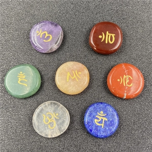 Macro shot of 7 natural chakra energy stones with golden engraved Sanskrit symbols