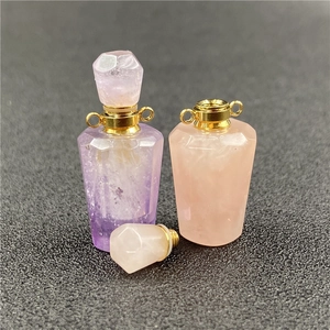 Macro shot of faceted amethyst and rose quartz heart perfume bottle pendants with gold caps