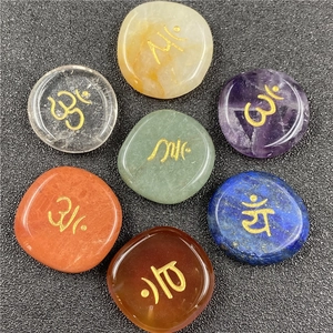 Macro view of seven colorful natural chakra stones with golden engraved symbols