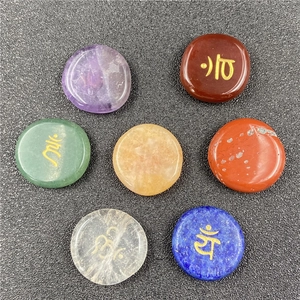 Macro view of seven chakra healing stones with golden symbols on a textured grey surface