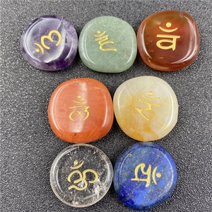 Macro detail of seven chakra stones with gold engraved Sanskrit symbols on a dark background