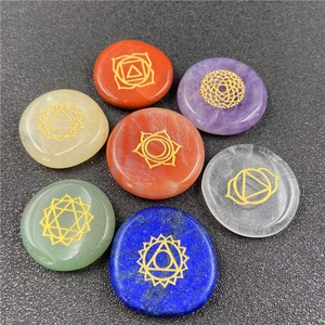 Detailed view of seven polished chakra stones with gold engraved symbols on stone surfaces