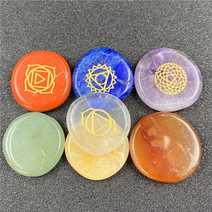 Detailed top view of seven chakra healing stones with golden symbols on black background