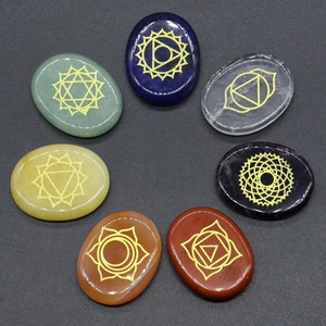 7 Chakra natural energy stones set with golden symbols on black sand background