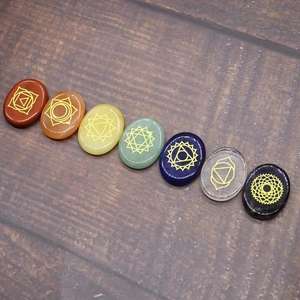 Polished seven chakra natural energy stones set with gold symbols on dark wood