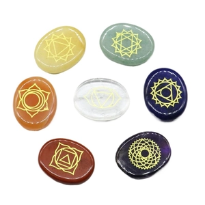 Polished seven chakra energy stone set with golden symbols on oval natural crystals
