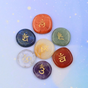 Set of 7 polished chakra healing stones with engraved gold symbols on starry background