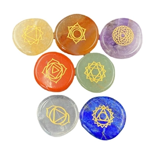 Natural 7 chakra healing crystal stones set with engraved gold symbols on white background