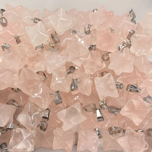 Macro view of rose quartz Merkaba pendants showing star shapes and natural textures