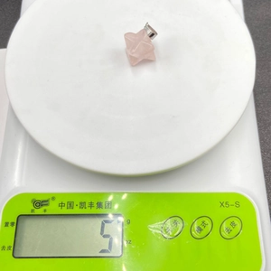 Close-up of a 5g pink crystal Merkaba star pendant on a scale showing its weight