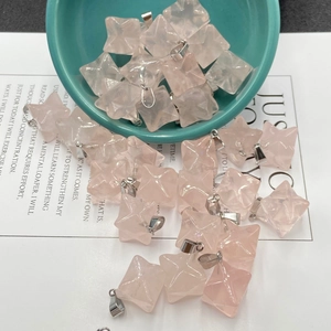 Detail of star-shaped rose quartz Merkaba pendants with silver bails on a ceramic plate