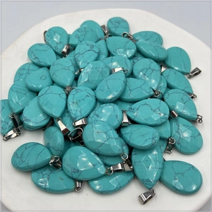 Close-up of teardrop turquoise pendants with natural black veins in a white tray