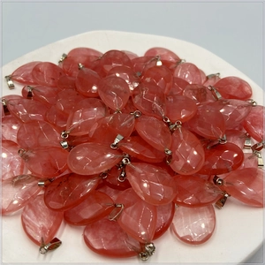 Close-up of faceted teardrop crystal stone pendants with silver metal clasps in a tray