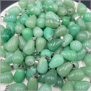 Macro shot of green teardrop stone pendants with silver clasps on a white tray