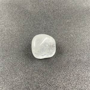 Polished natural white crystal stone with internal ice cracks on grey sand surface