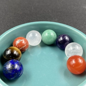 Eight natural crystal energy stones set in a ceramic dish, featuring colorful polished spheres