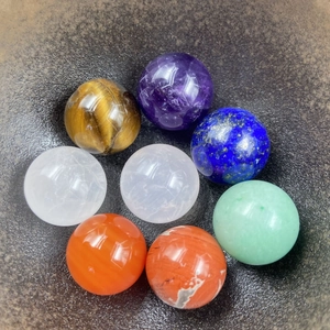 Macro shot of 8 polished chakra stone spheres in a dark bowl, highlighting crystal textures