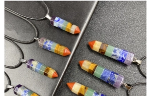 Macro detail of hexagonal prism seven chakra crystal pendants with black wax cord necklace