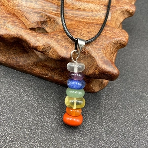 Detail of seven chakra natural stone pendant with colorful beads on black cord necklace