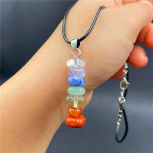 Detail view of a 7 Chakra natural gemstone pendant held by hand with black cord