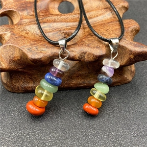 Close-up of Seven Chakra natural stone pendant necklace on a rustic wooden stand