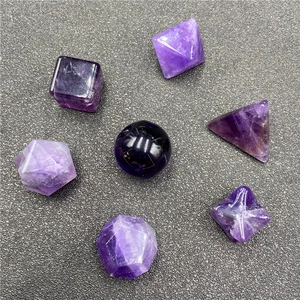 Macro view of seven assorted geometric amethyst crystals on a textured gray surface