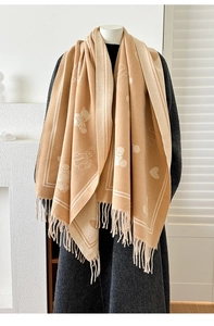 Détail macro du motif jacquard d'ours et de cœur sur un châle épais en cachemire beige