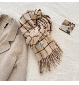Detailed view of beige plaid scarf with soft fringe edges and cozy thick texture