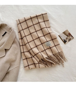 Close-up detail of beige plaid scarf showing soft tassels and thick woven texture