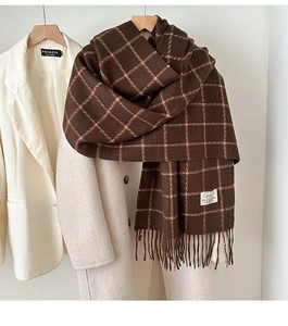 Close-up of thick plaid scarf texture with tassel detail and a white sewn-on label