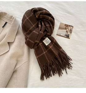 Close-up of brown plaid scarf with orange accents and stylish brand label detail