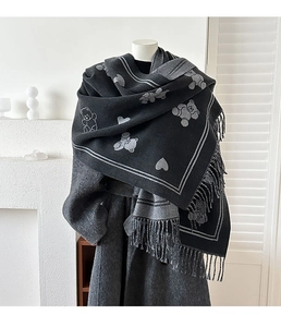 Détails de motifs ours et cœurs en jacquard sur une écharpe épaisse à franges