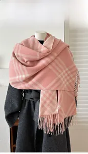 Detail of pink and white plaid cashmere-like scarf with long tassels on a grey coat